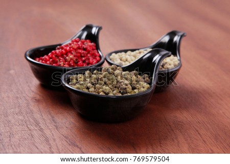 fresh dry peppercorn in small black bowl on wooden table ready to cook