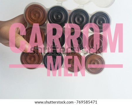 Word - CARROM MEN.Hand holding a carrom set men balls case with white background/selective focus.Conceptual image. 