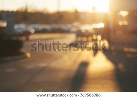 Blurred street background with car, people, shadows in evening sunlight.