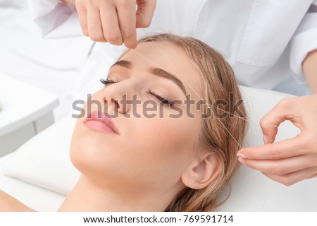 Young woman having eyebrow correction procedure in beauty salon Royalty-Free Stock Photo #769591714