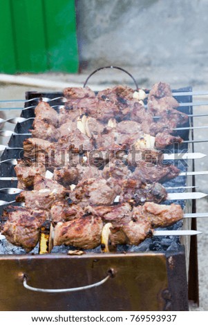 Grilled kebab cooking on metal skewer. Roasted meat cooked at barbecue. BBQ fresh beef meat chop slices. Traditional eastern dish, shish kebab. Grill on charcoal and flame, picnic, street food