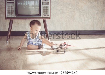 Asian cute baby boy playing with a plane model.vintage tone style