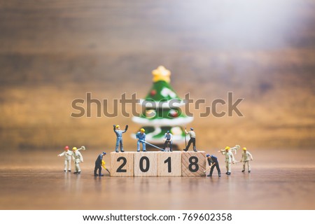 Miniature people : worker team building wooden block number 2018 on wooden background, Christmas celebration concept.