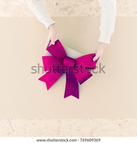 Female hands holding big bow on table