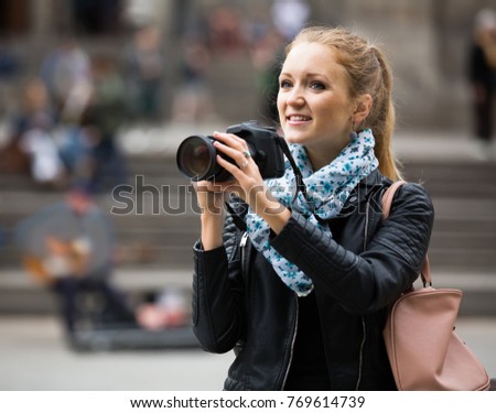Young european woman walking in autumn city with digital camera