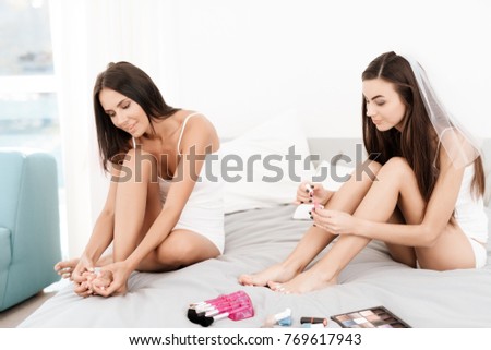 Girls have a great time at the hen-party. Close-up photo of bridesmaids and bride celebrating. Girls in a veil are sitting on the bed. They do make-up and get ready for the wedding.