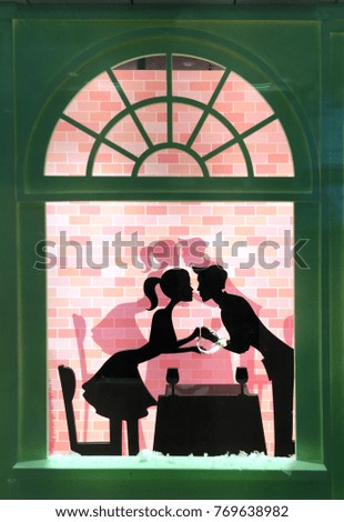 cartoon cutout of a kissing couple in a cutout window