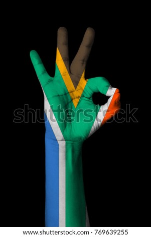 Hand making Ok sign, South africa flag painted as symbol of best quality, positivity and success - isolated on black background