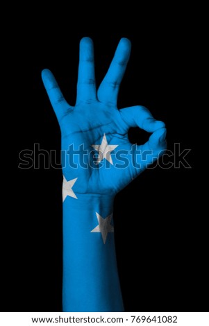 Hand making Ok sign, Micronesia flag painted as symbol of best quality, positivity and success - isolated on black background
