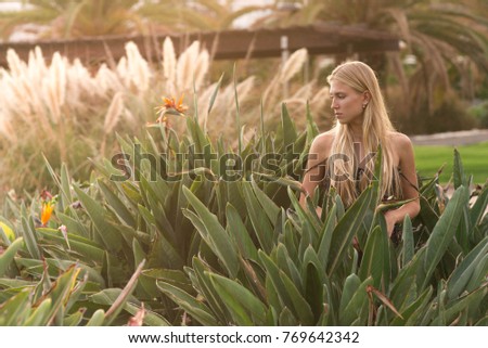 Photo of a girl in a park looking at plants. Sunset in the garden.Gran Canaria,Spain