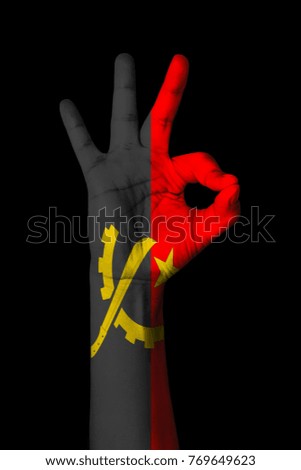 Hand making Ok sign, Angola flag painted as symbol of best quality, positivity and success - isolated on black background