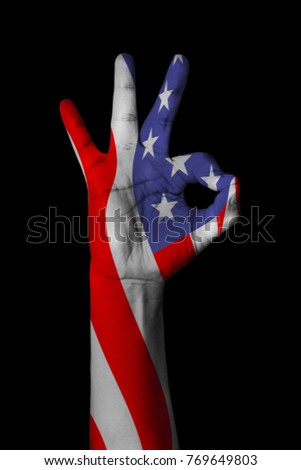 Hand making Ok sign, American flag painted as symbol of best quality, positivity and success - isolated on black background