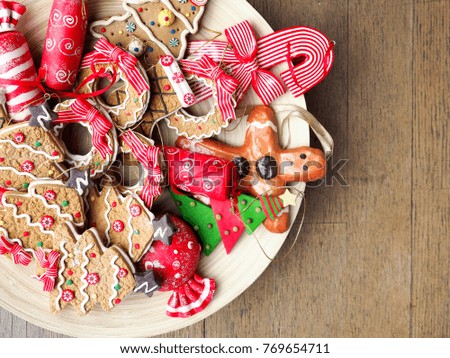 Close up of Wood plate full of Christmas ornaments that look likes cookies on wooden table on a bright sunny day.