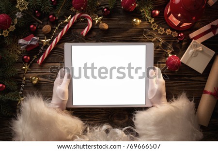 Close up of Santa Claus hands holding blank digital tablet with copy space 