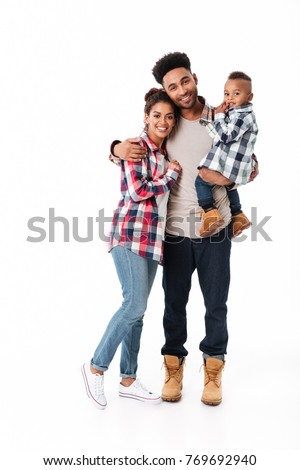 Full length portrait of a happy young african family with their little son standing together isolated over white background