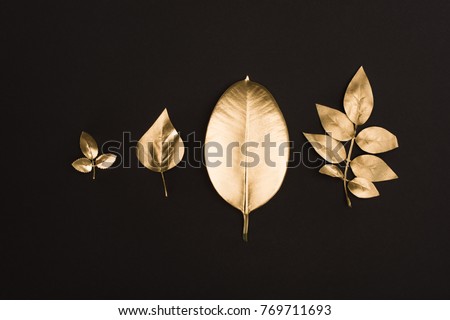 close up view of shiny golden leaves arranged in line isolated on black