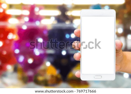 Man use mobile phone, blur image of christmas tree shop as background.