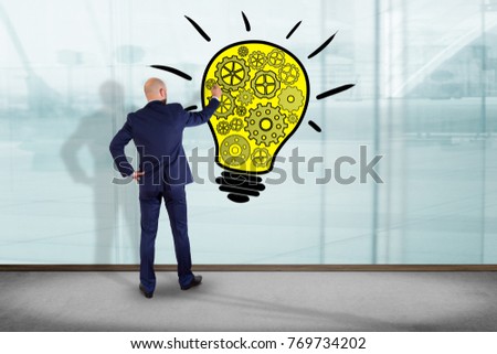 View of a Businessman in front of a wall drawing a bulb lamp idea - Creative concept