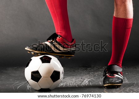 legs of soccer player with ball on dark background Royalty-Free Stock Photo #76974130