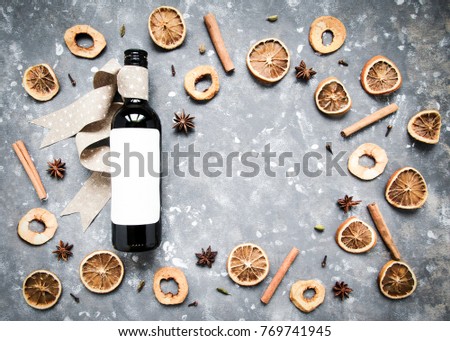 Bottle of red wine and ingredients and spices for cooking mulled wine on bright blue winter background. Flat lay. 