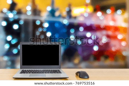 Computer on the table, blurred picture of the beautiful Christmas shop as background.