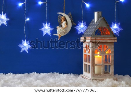 Wooden old house with candle and fairy on the moon over the snow and blue background