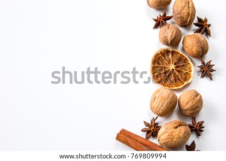 Frame of spilled Christmas products: whole walnuts, slice of dry orange, anise stars and cinnamon sticks. White background. Free place for pasting title or writing text. Empty half of picture