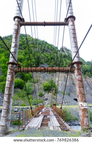 Suspension bridge. Old ruined road bridge over a mountain river during a rain in Georgia