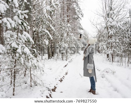 Beautiful young girl makes selfie in a snowy, frosty forest