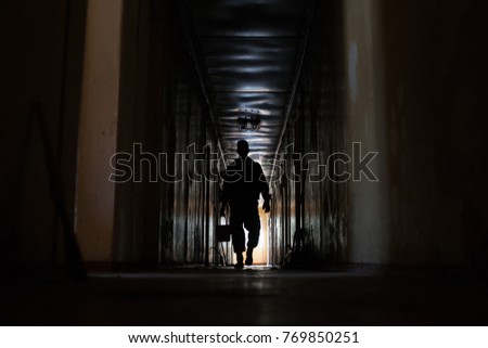 Silhouette of a soldier who walks the corridor of the barracks with a bucket. The soldier is going to do the cleaning. Grained photo