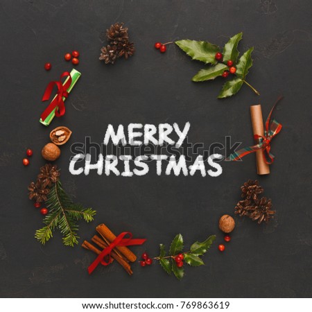 Merry christmas greeting, decoration background. Top view on xmas handmade wreath frame with wooden letters on black backdrop