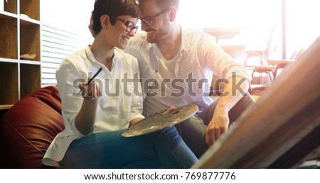 Beautiful young woman and a handsome man attending a painting workshop together