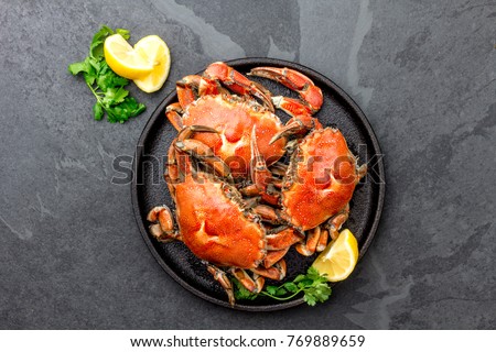 Cooked crabs on black plate served with white wine, black slate background, top view. Royalty-Free Stock Photo #769889659