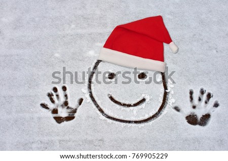 Funny face, painted on snow, in Santa's hat