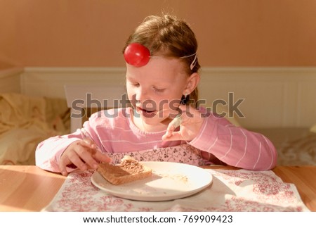 Kid girl eats chocolate cream spread on bread. girl smiles. Playful little girl wears clown nose. Childhood and fun concept