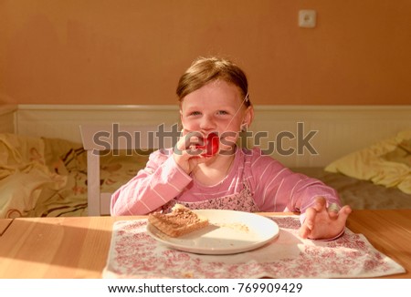 Kid girl eats chocolate cream spread on bread. girl smiles. Playful little girl wears clown nose. Childhood and fun concept