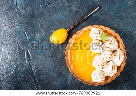 Fresh homemade lemon tartlets with meringue on blue background,top view.