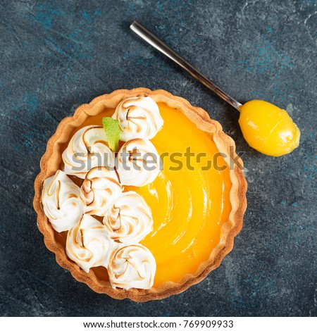 Fresh homemade lemon tartlets with meringue on blue background,top view.