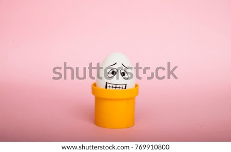 Egg with funny face in the package on a pinkbackground. Easter Concept Photo. Eggs. Faces on the eggs Eggs