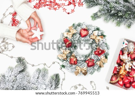 Christmas composition. Preparation for the holiday, women's hands with festive decorations. Christmas or New Year. Xmas wreath of fir branches, snowflakes, gifts, pine branches, toys on a white backgr