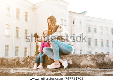 Young mom and cheerful adorable blond girl playing, having fun