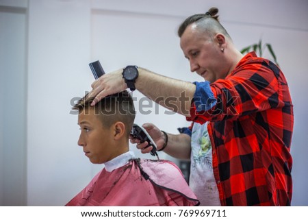 Portrait of a modern young boy in barber chair, getting a urban hairstyle