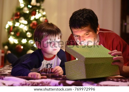 Father gives Christmas gift to his little son for a New Year. Dan and son opening Christmas presents