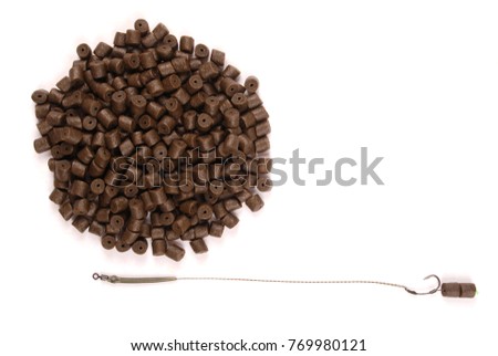 Fishing bait with hook and brown pre-drilled halibut pellets for carp fishing isolated on white background with soft shadow