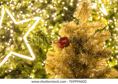 Christmas festival  in Bangkok. Golden Christmas tree with red ball and  yellow bokeh background with golden star light.
