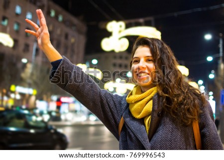 Girl calling taxi in urban environment at night