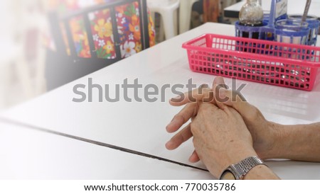 soft, bright shot of an old man's hands putting together on a white table waiting for his ordered food to be served at restaurant in Yaowarat, Bangkok, Thailand
