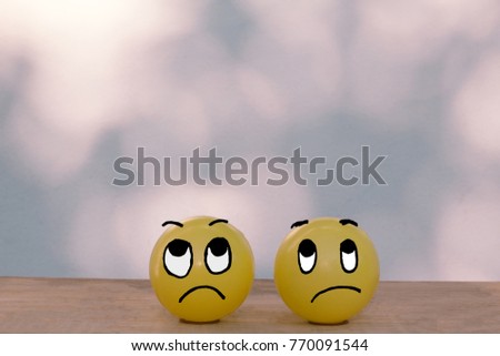 Two sad moody face yellow ball on wooden table and bokeh wall with copy space