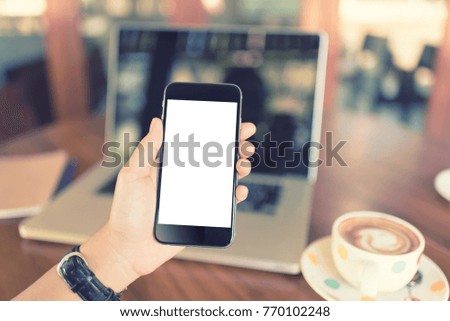 hand holding smartphone white screen. using mobile phone in coffee shop. vintage tone
