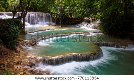 Beautiful clear green waterfall in the fertile forest Water flows down through the rock in a beautiful stream at Luang Prabang, Laos.